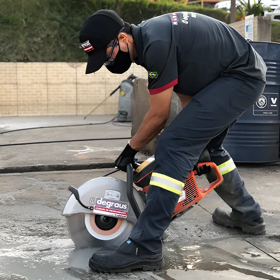 Operador cortando piso de concreto com cortadora de disco, em EPI completo
